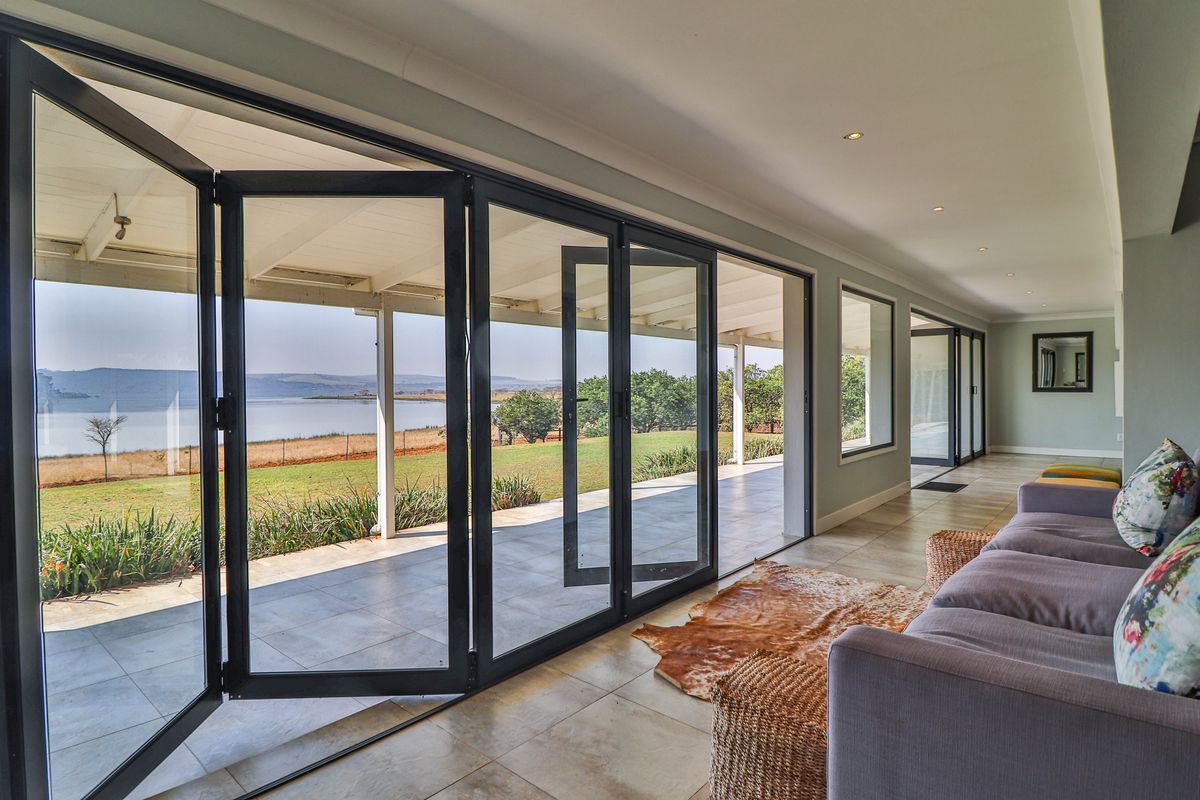 Spacious living area featuring large black-framed bi-fold doors that open onto a covered patio with scenic lake views.