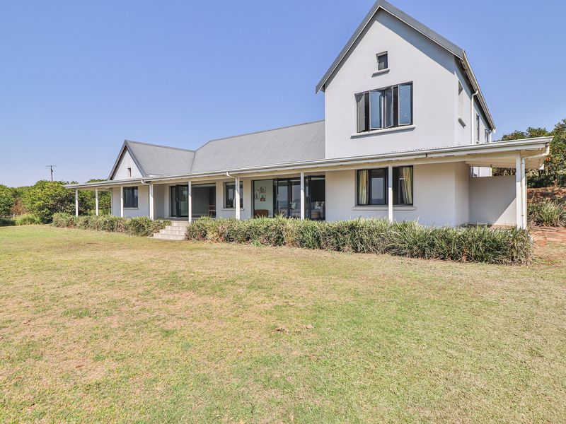 Rear view of a two-story house featuring a covered patio, large sliding glass doors, and a well-maintained lawn.