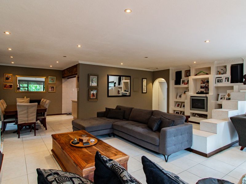 Spacious open-plan living and dining area featuring tiled flooring, recessed lighting, and a large built-in shelving unit.