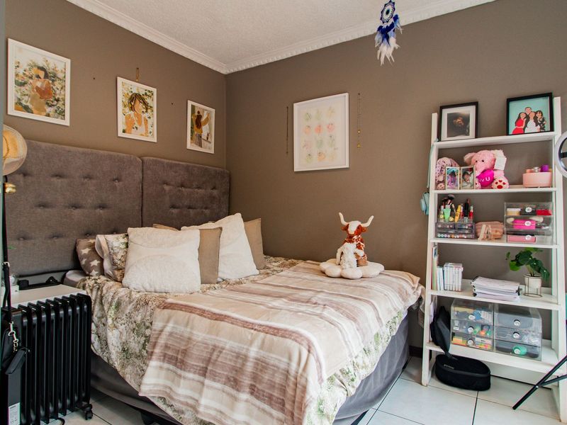 A cozy bedroom featuring tiled flooring, decorative cornice, and window blinds, providing a comfortable and functional living space.