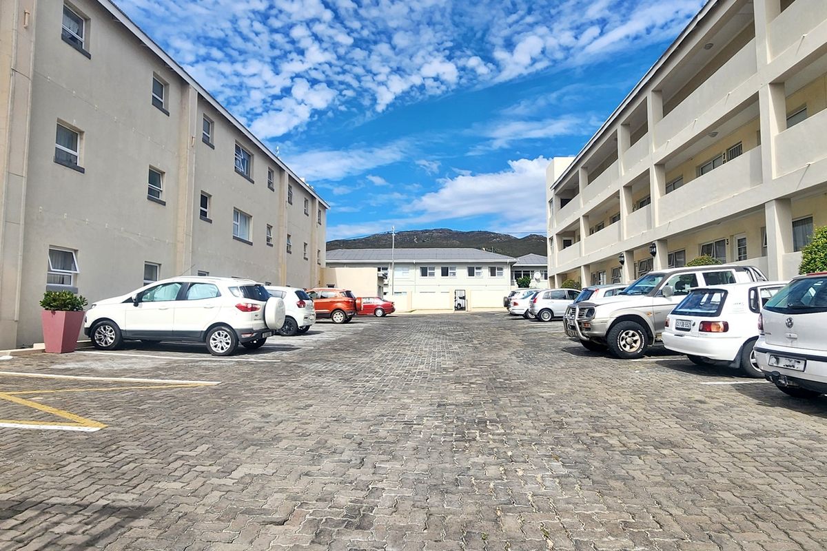 Exterior view of an apartment complex courtyard featuring paved parking areas and multi-story residential building facades.