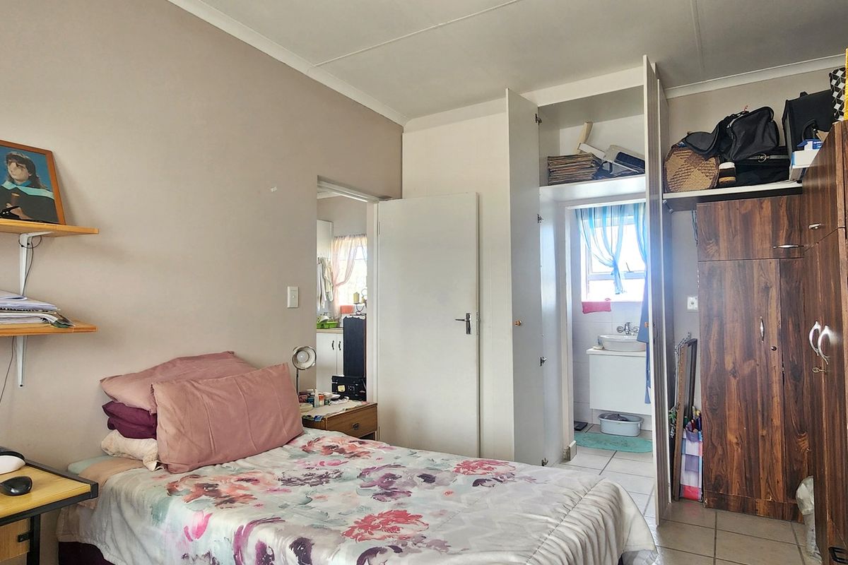 A functional bedroom featuring built-in cupboards and tiled flooring, with an adjoining view into a small bathroom area.
