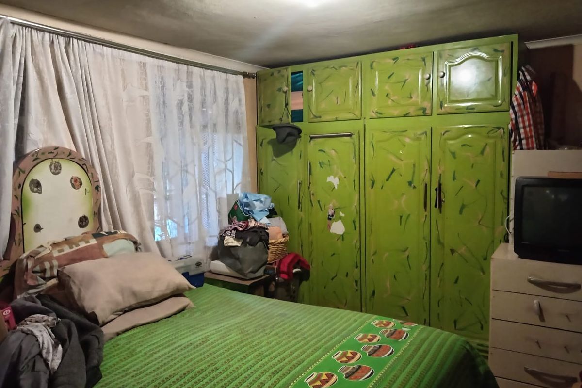 A bedroom featuring built-in green cabinetry with overhead storage, providing functional storage space within the room.