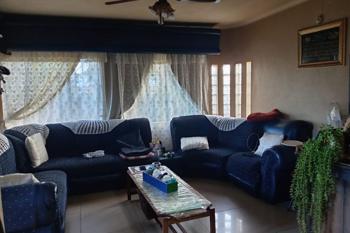 A comfortable living room featuring tiled flooring, a ceiling fan, and decorative glass block accents, providing a functional space for relaxation.