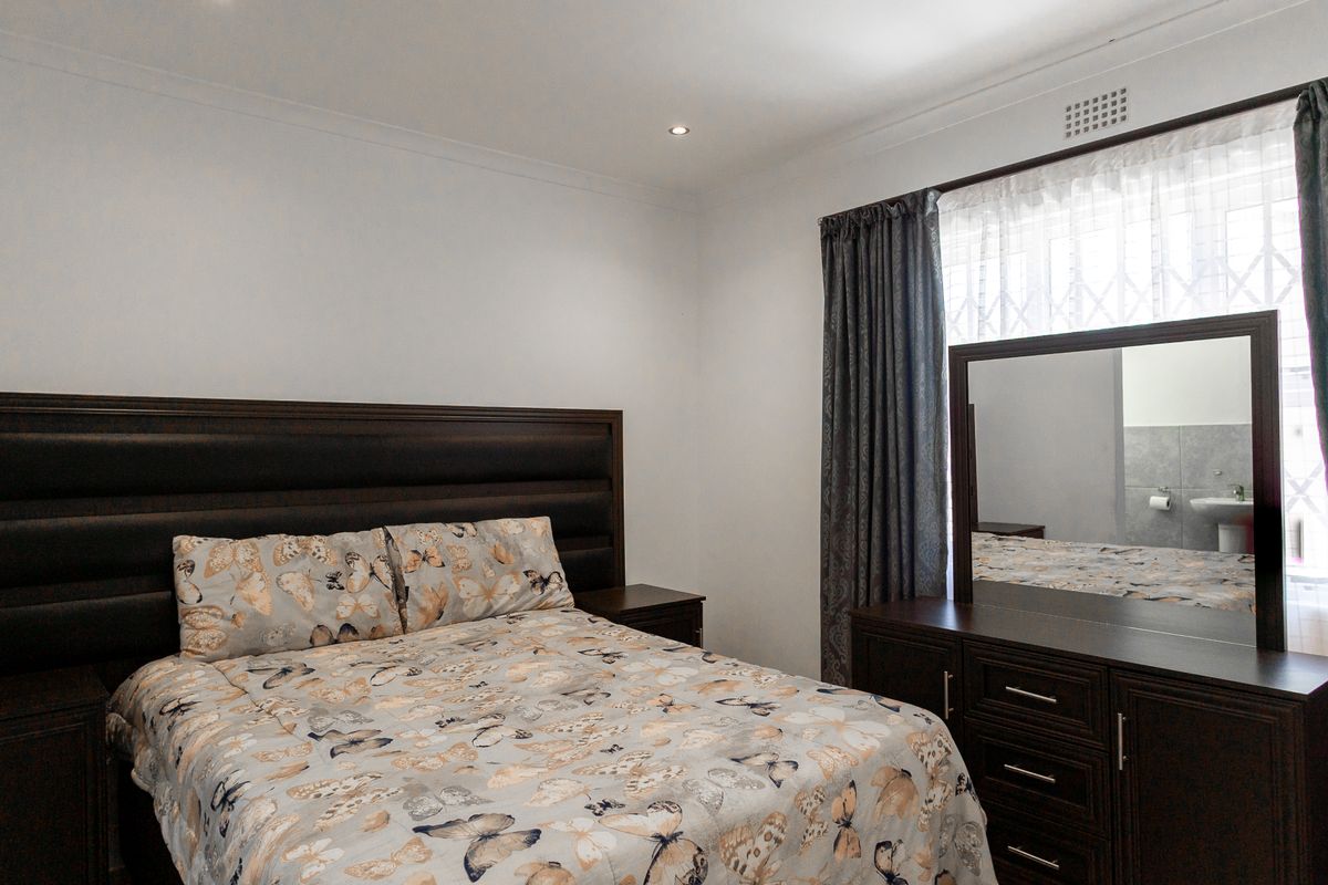 A well-maintained bedroom featuring recessed downlighting, coving, and a security gate on the window.