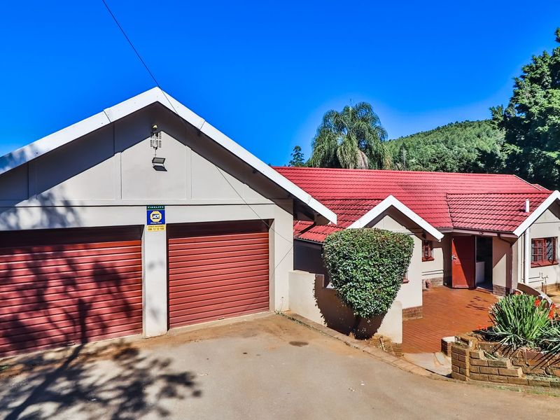 Front elevation of a residential property featuring a double garage, red tiled roof, and a paved driveway entrance.