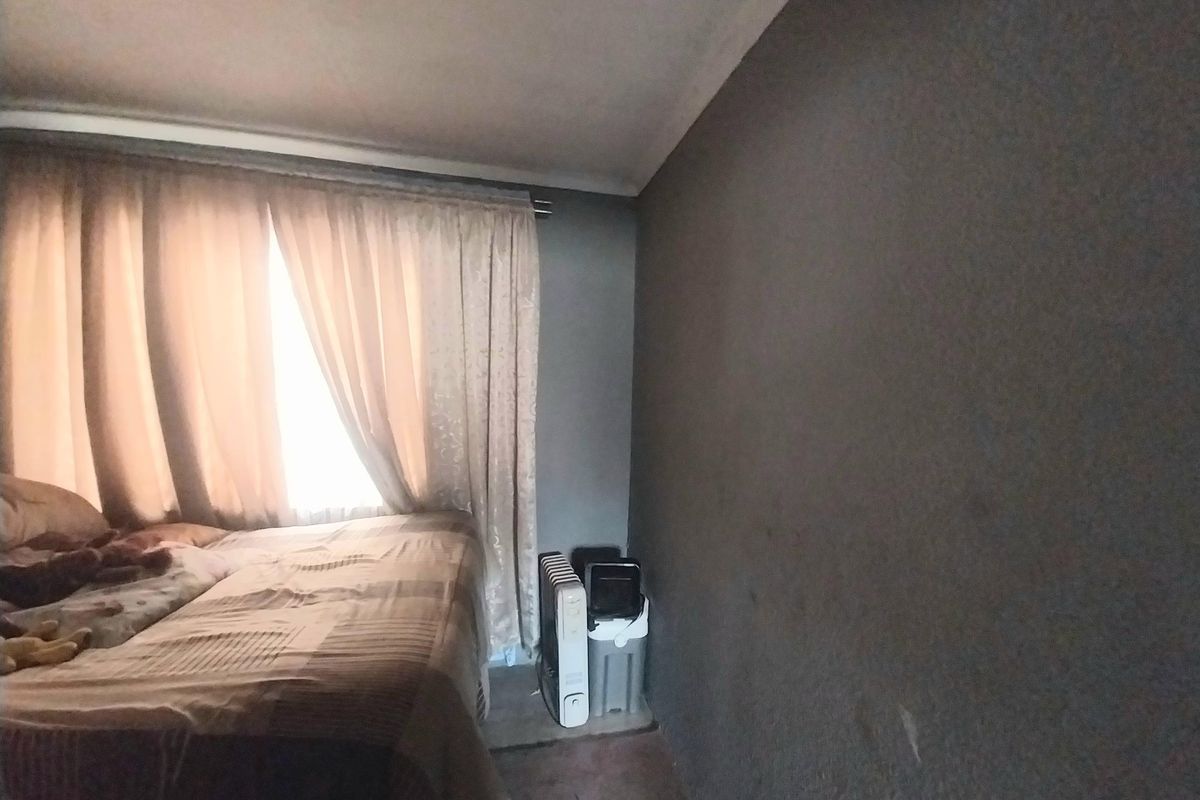 A bedroom featuring dark-toned walls, a window with curtains, and carpeted flooring.