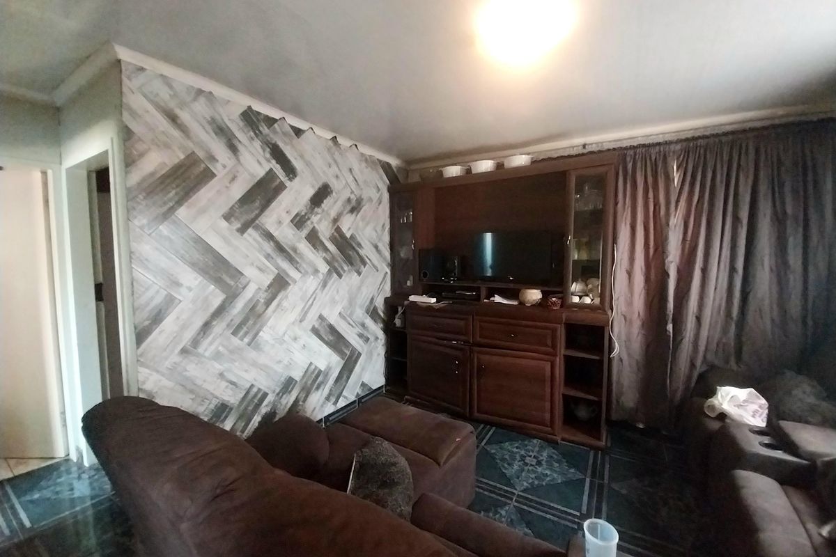 A living room featuring a decorative herringbone-patterned feature wall and tiled flooring.