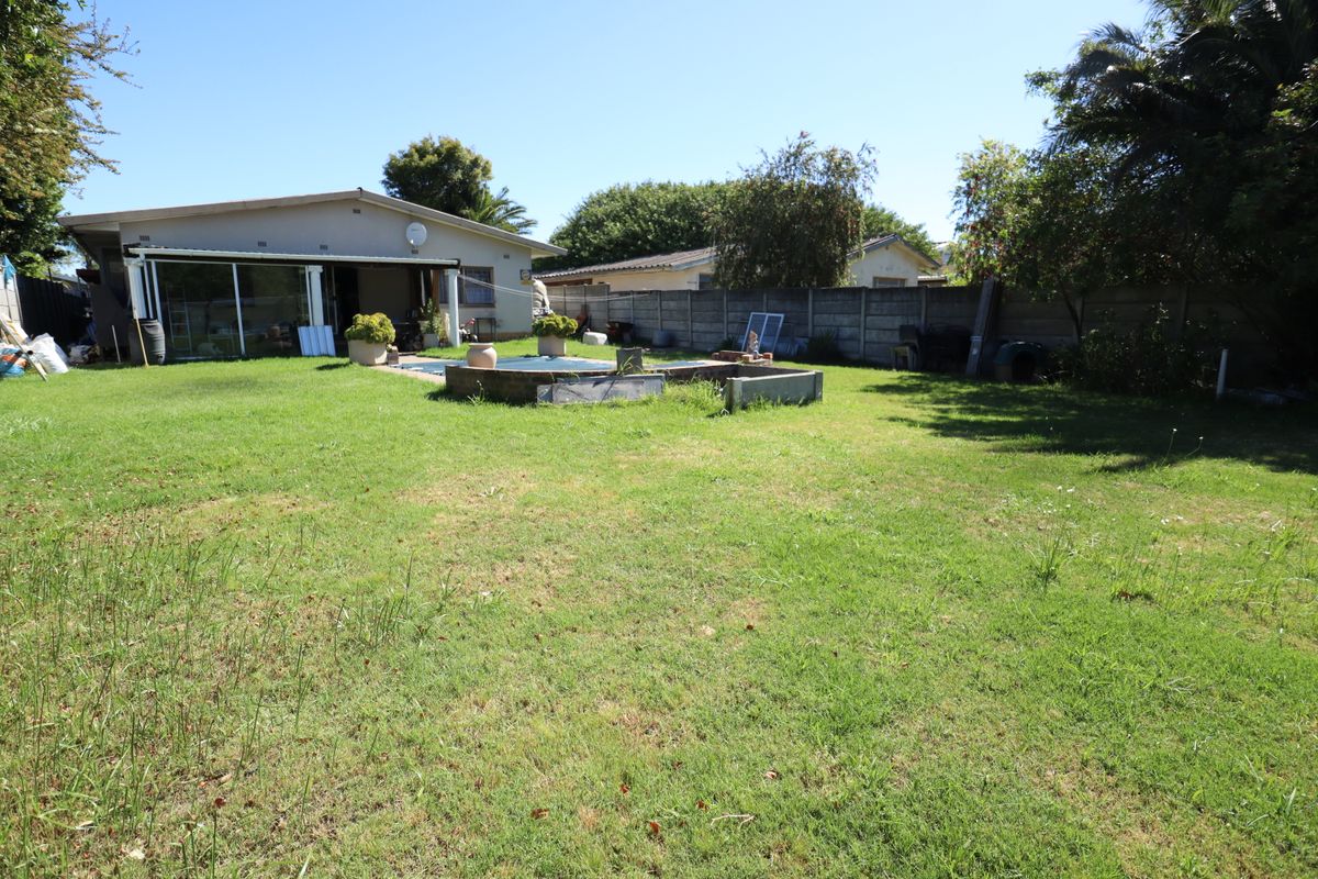 Spacious rear garden featuring a swimming pool, covered patio area, and concrete boundary walls, offering potential for landscaping and outdoor living improvements.