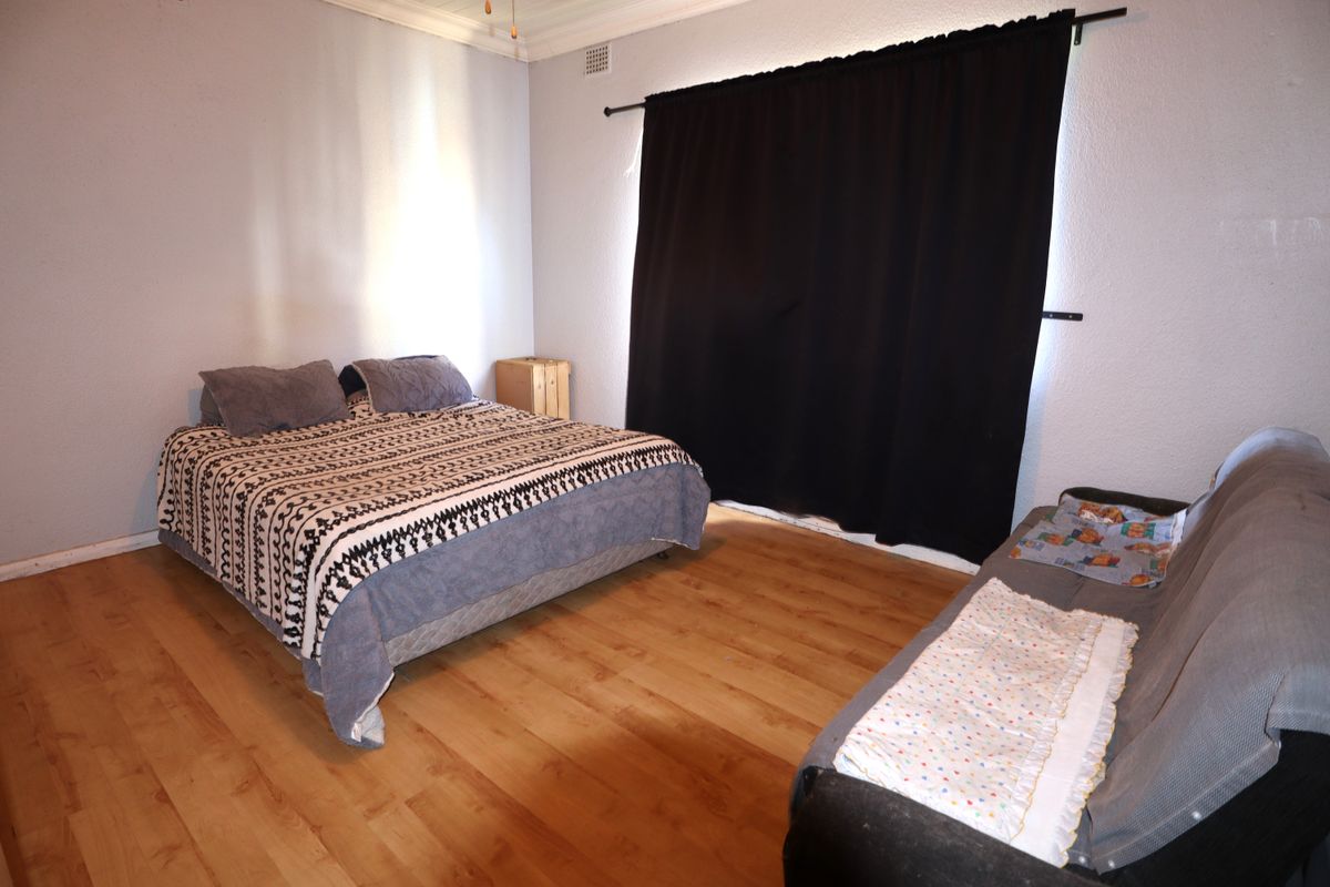 A spacious bedroom featuring laminate flooring and neutral wall finishes, offering a functional layout with ample room for bedroom furniture.