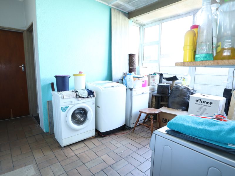 A functional laundry area featuring tiled flooring and large windows, providing ample natural light for utility tasks.