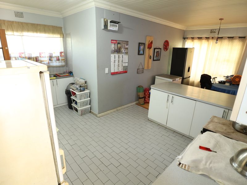 A functional kitchen space featuring tiled flooring, built-in cabinetry with laminate countertops, and a sink, offering potential for modernization and layout optimization.