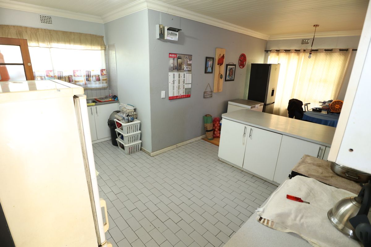 A functional kitchen space featuring tiled flooring, built-in cabinetry with laminate countertops, and a sink, offering potential for modernization and layout optimization.