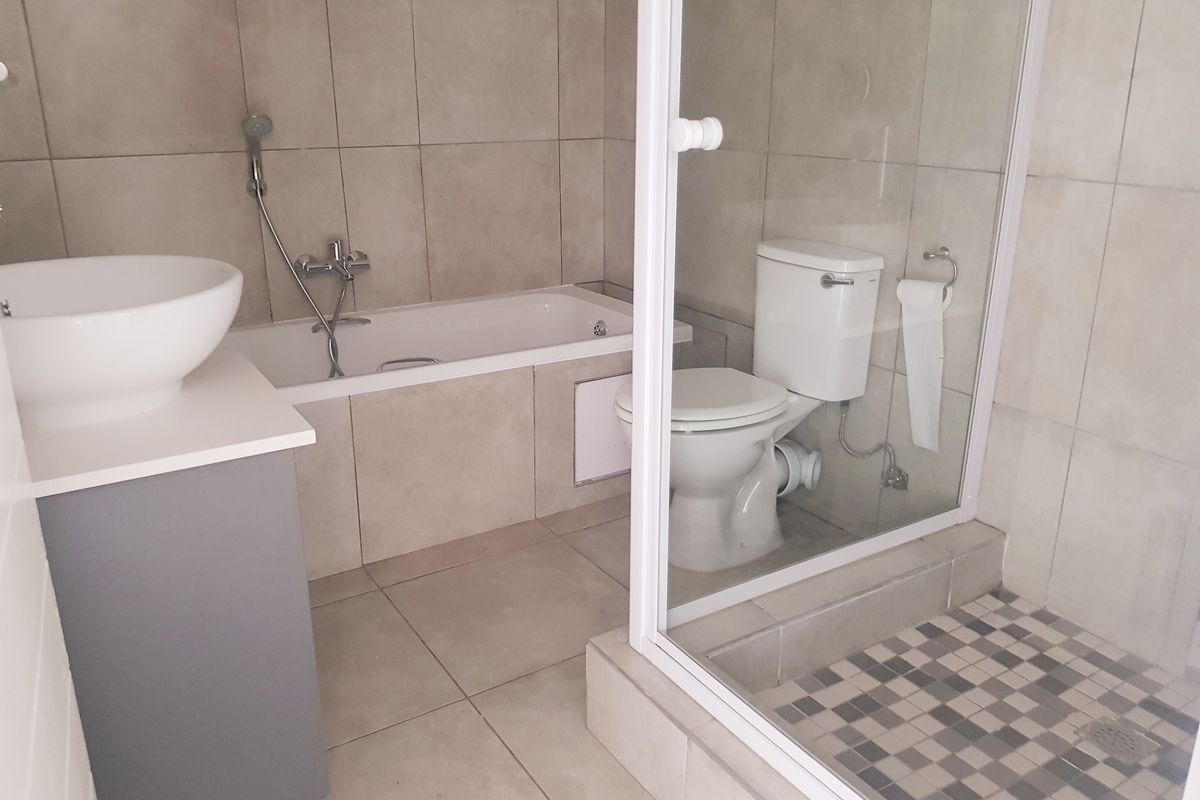 A clean, modern bathroom featuring a bathtub, separate glass-enclosed shower, toilet, and a contemporary vanity with a vessel sink.