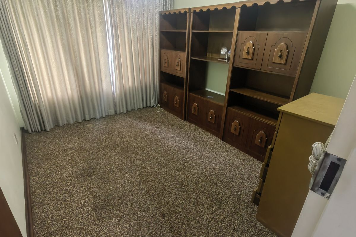A bedroom featuring fitted wooden cabinetry and carpeted flooring, offering potential for modernization and updated interior finishes.