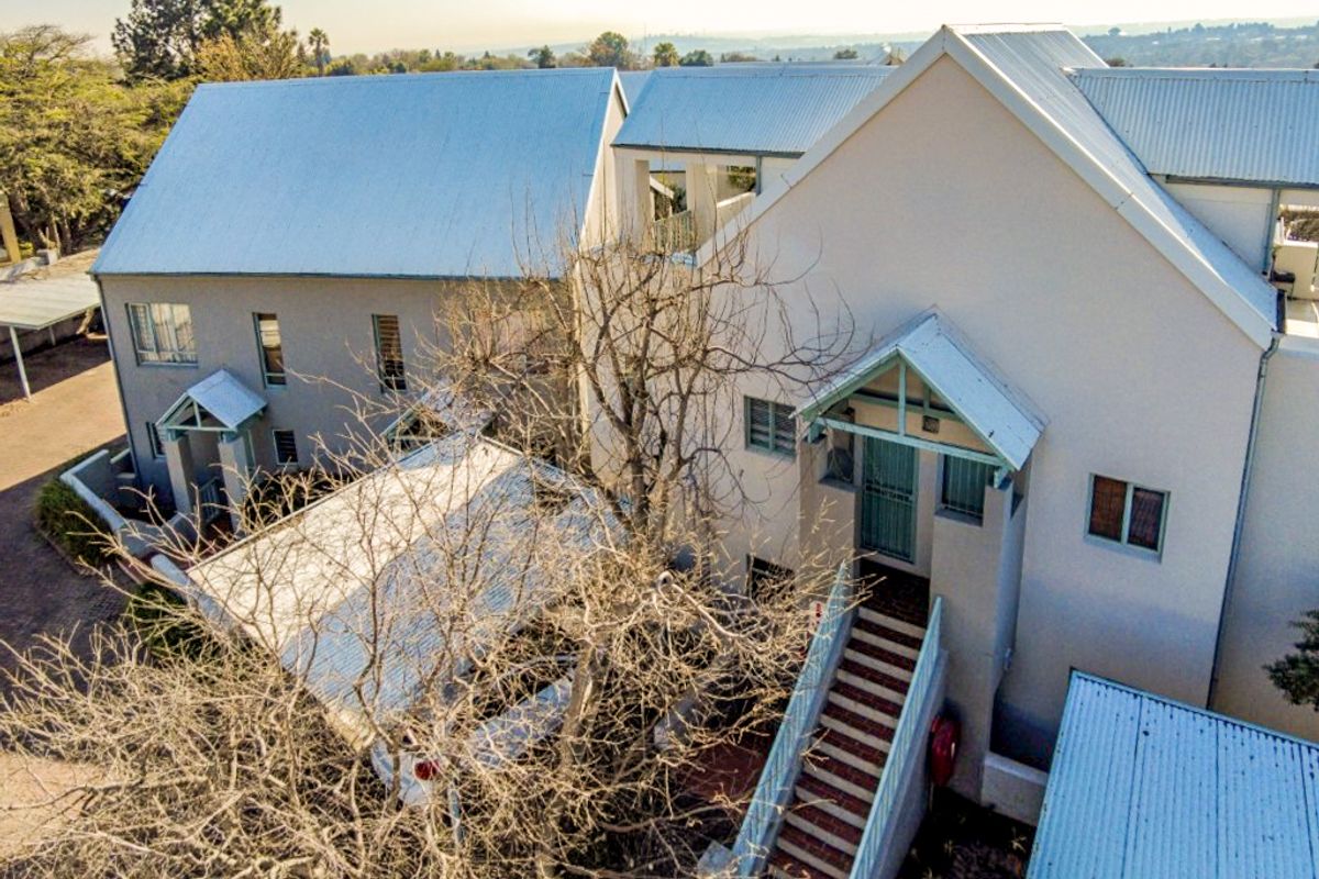 Aerial view of the apartment complex featuring pitched metal roofing, external staircases, and paved walkways.