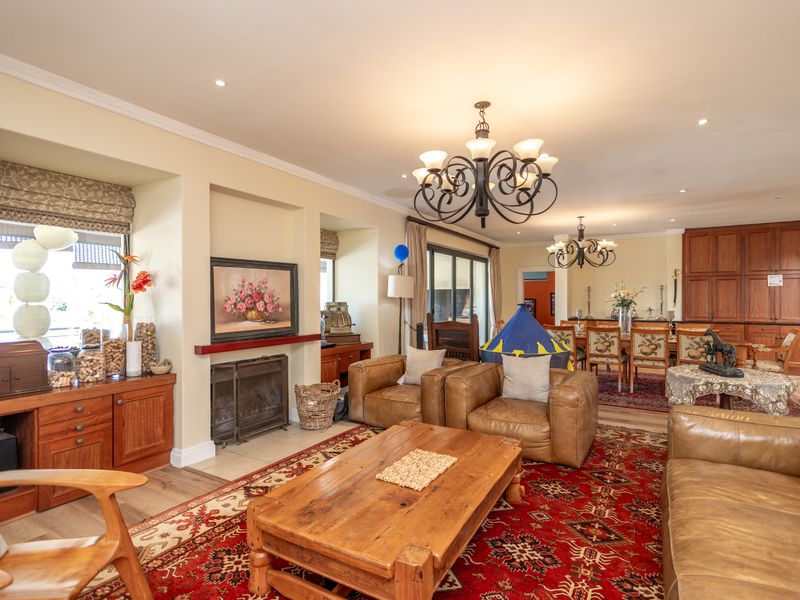 Spacious open-plan living and dining area featuring a recessed fireplace, built-in cabinetry, and elegant chandeliers, offering a warm and inviting atmosphere.