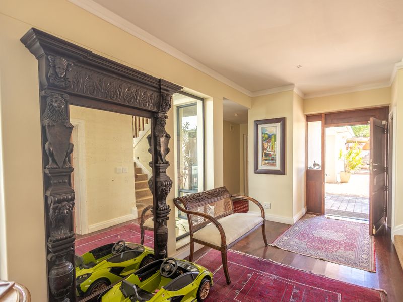 A welcoming entrance hall featuring hardwood flooring, a timber front door, and a staircase leading to the upper level.