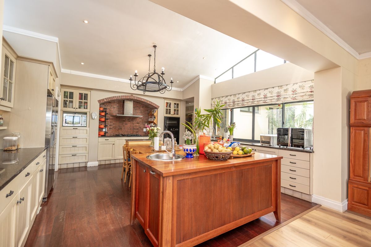 Spacious kitchen featuring a large wooden island, brick feature wall, custom cabinetry, and a bright skylight, creating a warm and functional culinary space.