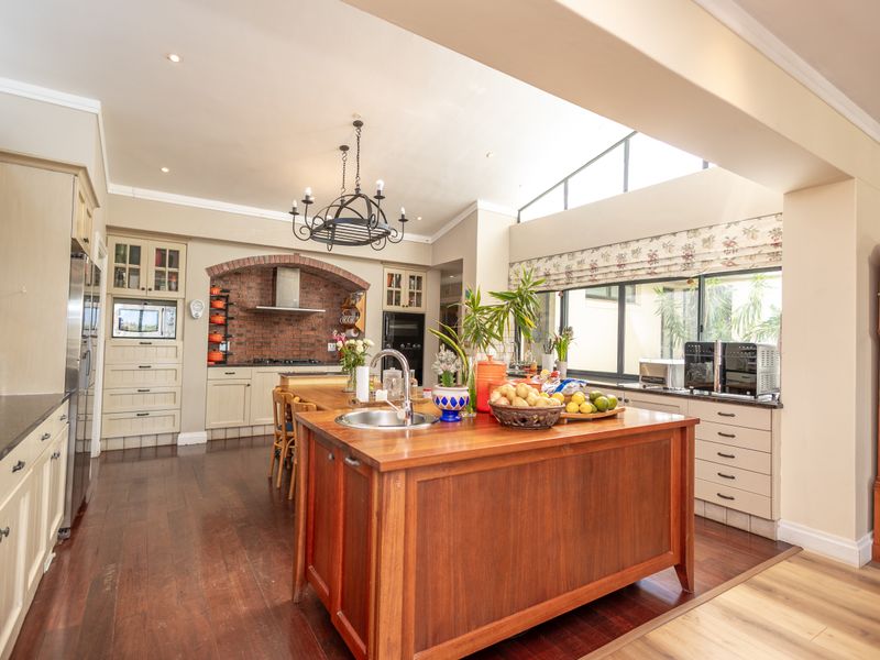 Spacious kitchen featuring a large wooden island, brick feature wall, custom cabinetry, and a bright skylight, creating a warm and functional culinary space.