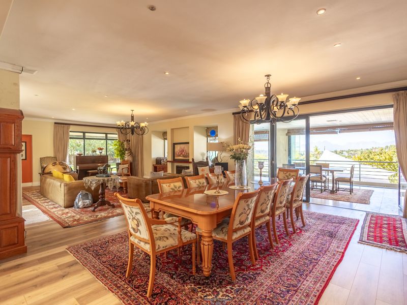 Spacious open-plan dining and living area featuring hardwood flooring, recessed lighting, a fireplace, and large sliding doors opening to a balcony with scenic views.
