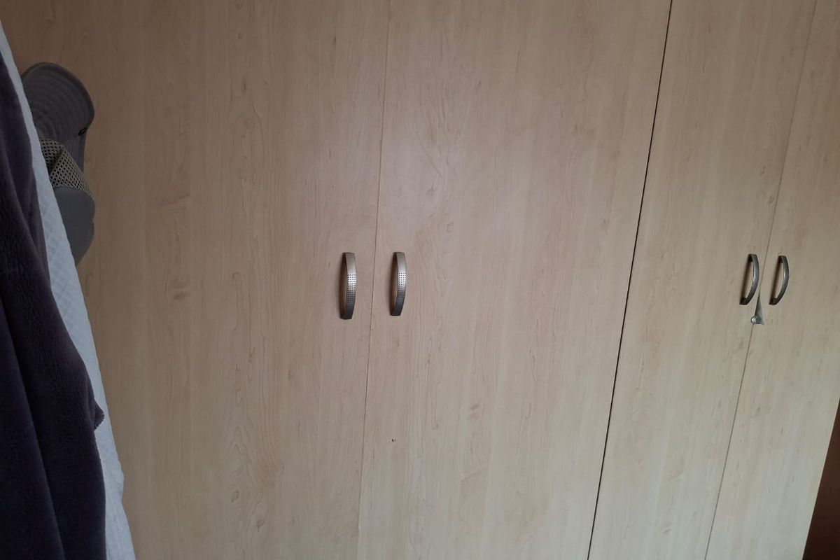 A view of built-in wooden bedroom cupboards with modern metal handles.