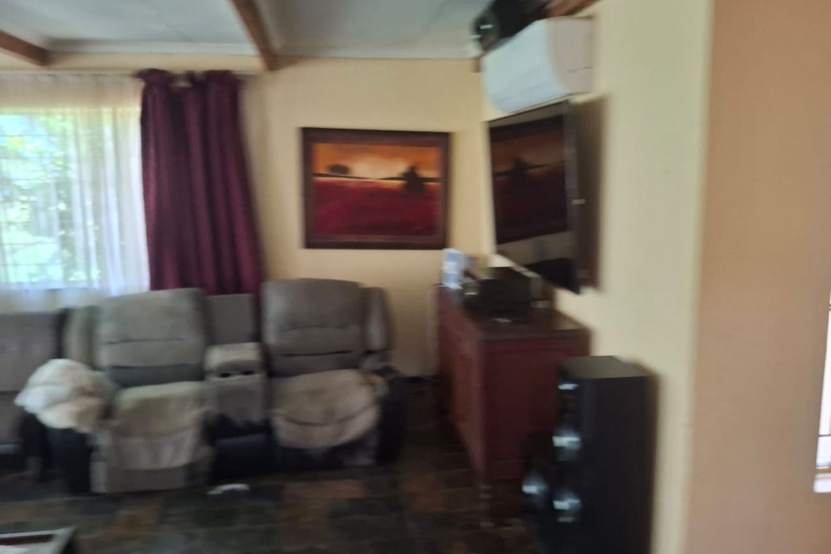 A living room featuring tiled flooring, exposed ceiling beams, and a wall-mounted air conditioning unit.