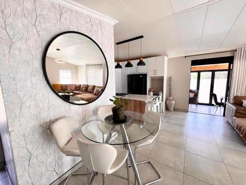 An open-plan living and dining area featuring tiled floors, a modern kitchen island with pendant lighting, and sliding doors leading to an outdoor space.