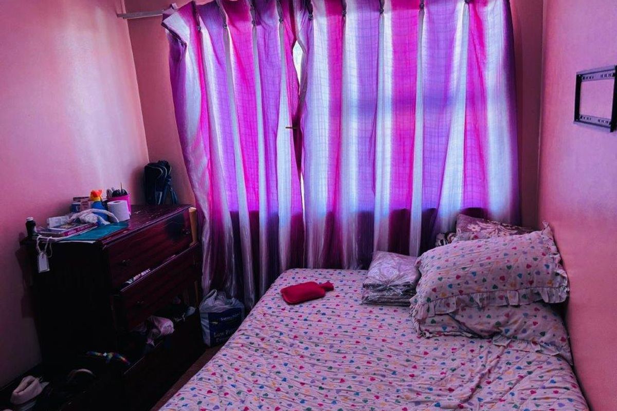 A compact bedroom featuring a window with curtains and standard wall finishes, suitable for a single bed setup.