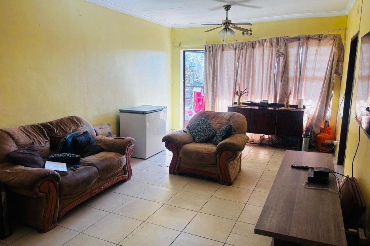 A living room featuring tiled flooring, a ceiling fan, and access to an outdoor area through a glass door.