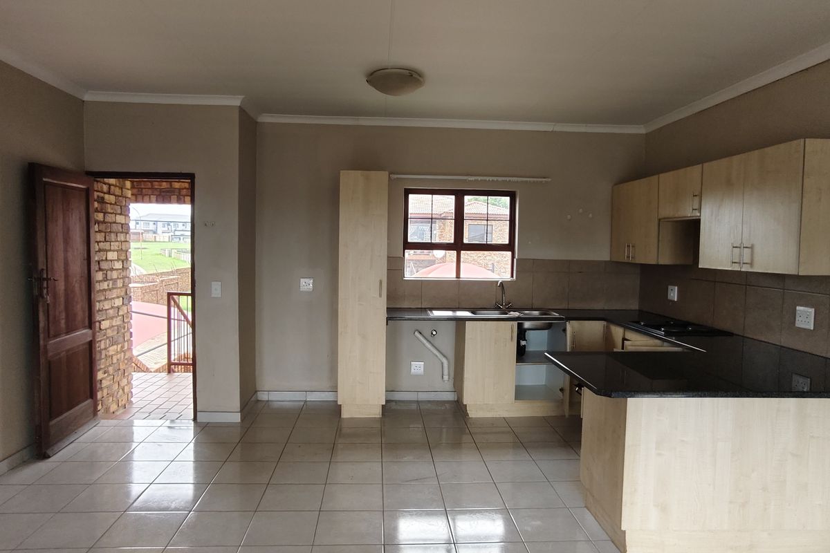 Open plan kitchen and living area featuring tiled floors, built-in cabinetry with granite countertops, and direct access to an outdoor balcony.