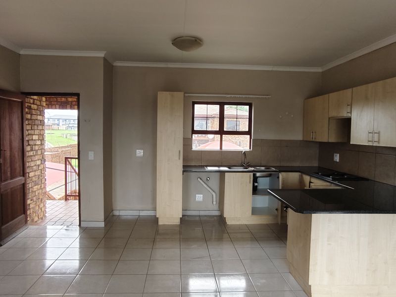 Open plan kitchen and living area featuring tiled floors, built-in cabinetry with granite countertops, and direct access to an outdoor balcony.