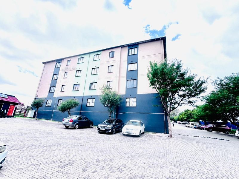 Exterior view of the Fleur-de-Lys apartment building featuring a multi-story facade with paved parking area in the foreground.