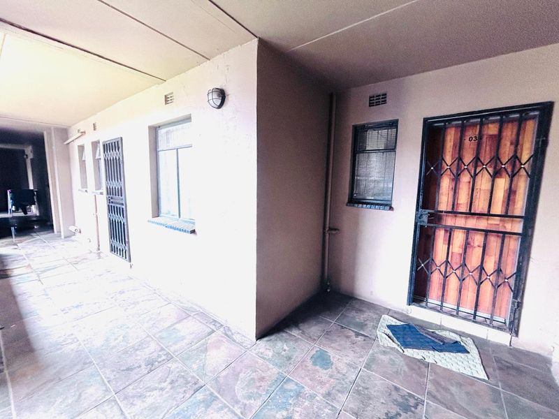 Apartment entrance area featuring tiled flooring, security gates, and exterior wall lighting, providing access to the unit.