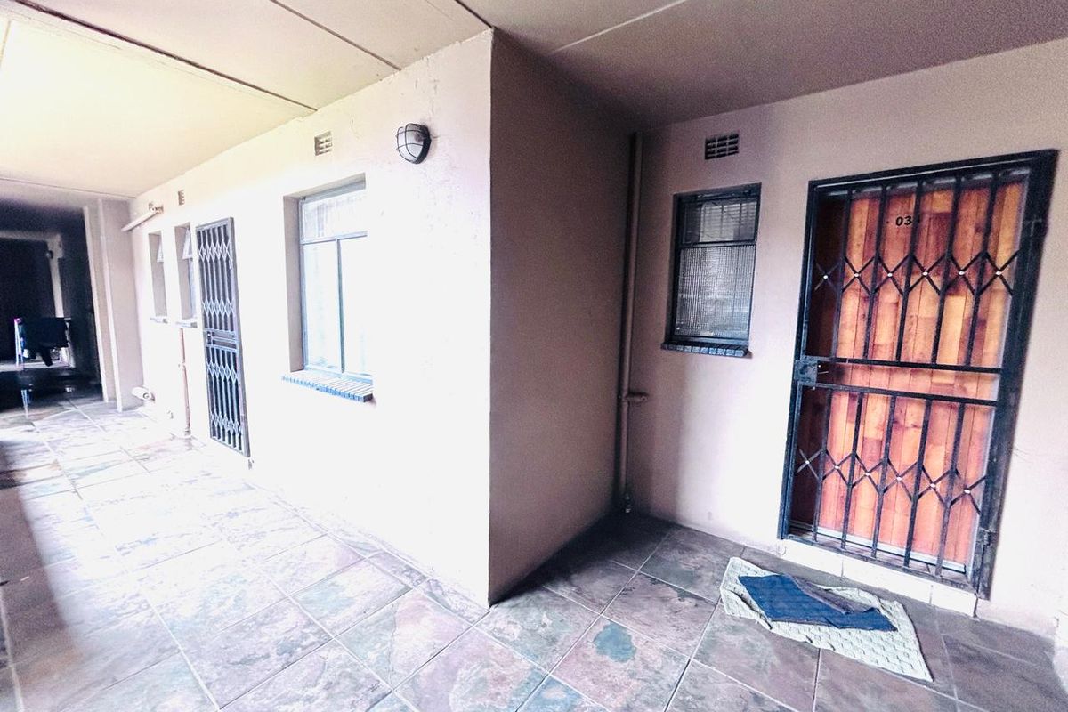 Apartment entrance area featuring tiled flooring, security gates, and exterior wall lighting, providing access to the unit.