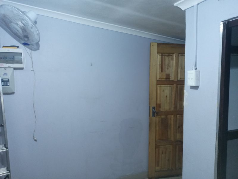 A utility area featuring a wall-mounted electrical distribution board, surface-mounted wiring, and a timber panel door.
