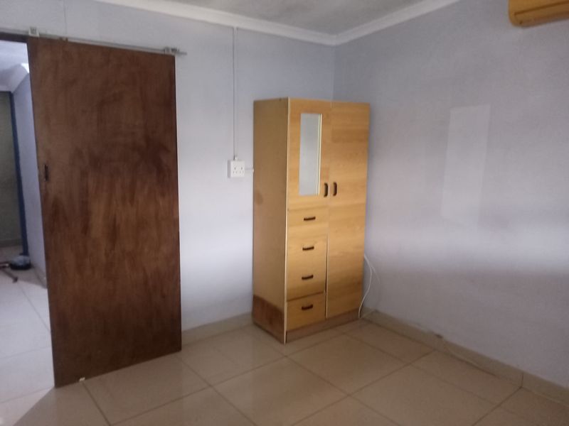 A bedroom featuring tiled flooring, a sliding door, and coving. The space requires cosmetic updates to improve its overall condition and appeal.