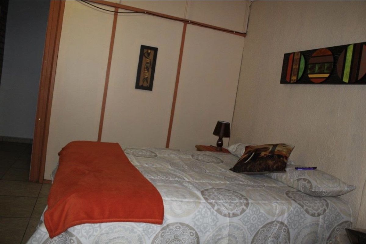 A bedroom featuring built-in wardrobes and tiled flooring, offering a functional space with potential for modern updates.