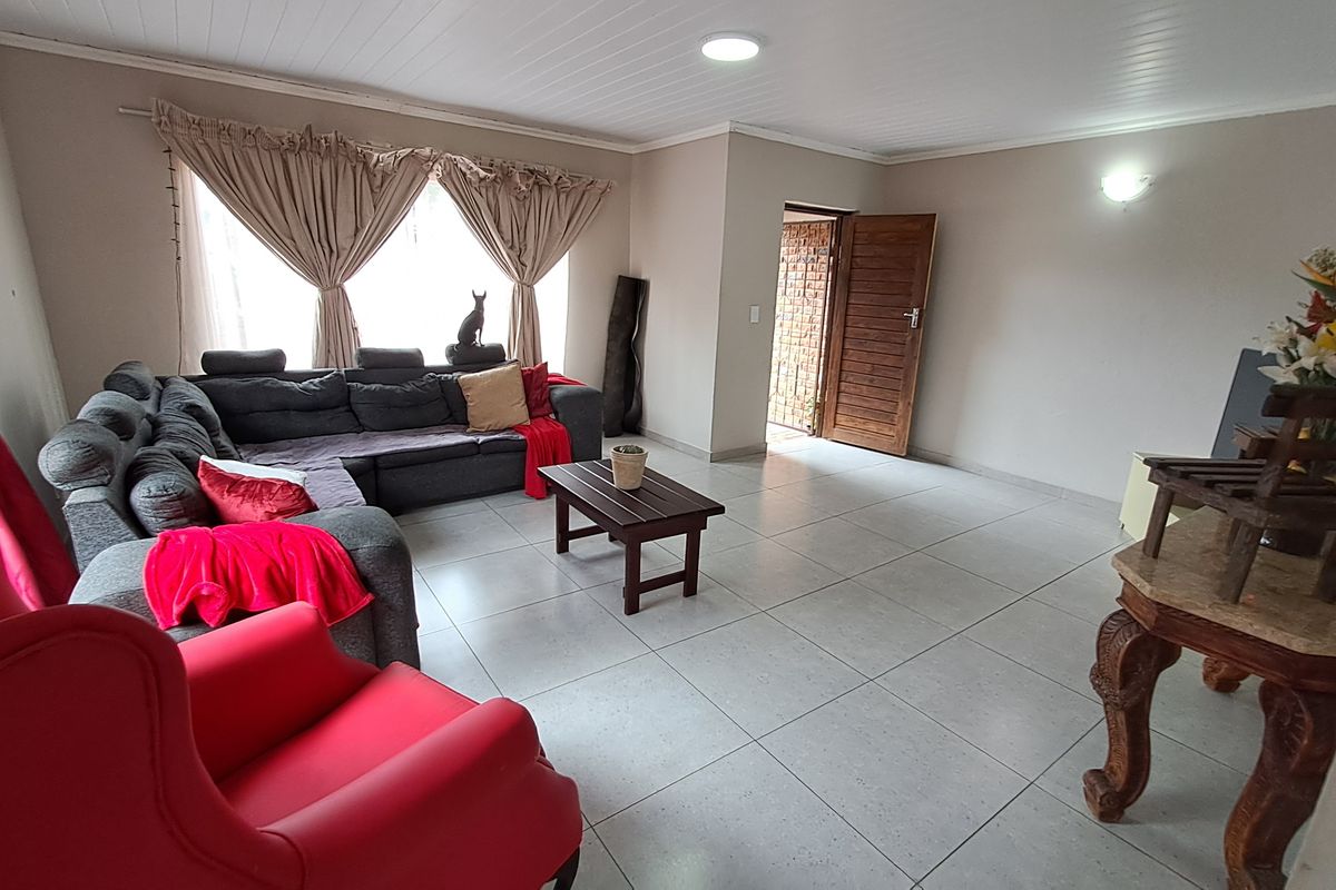 Spacious living room featuring neutral tiled flooring and a tongue and groove ceiling, offering a functional layout with direct access to an adjacent room.