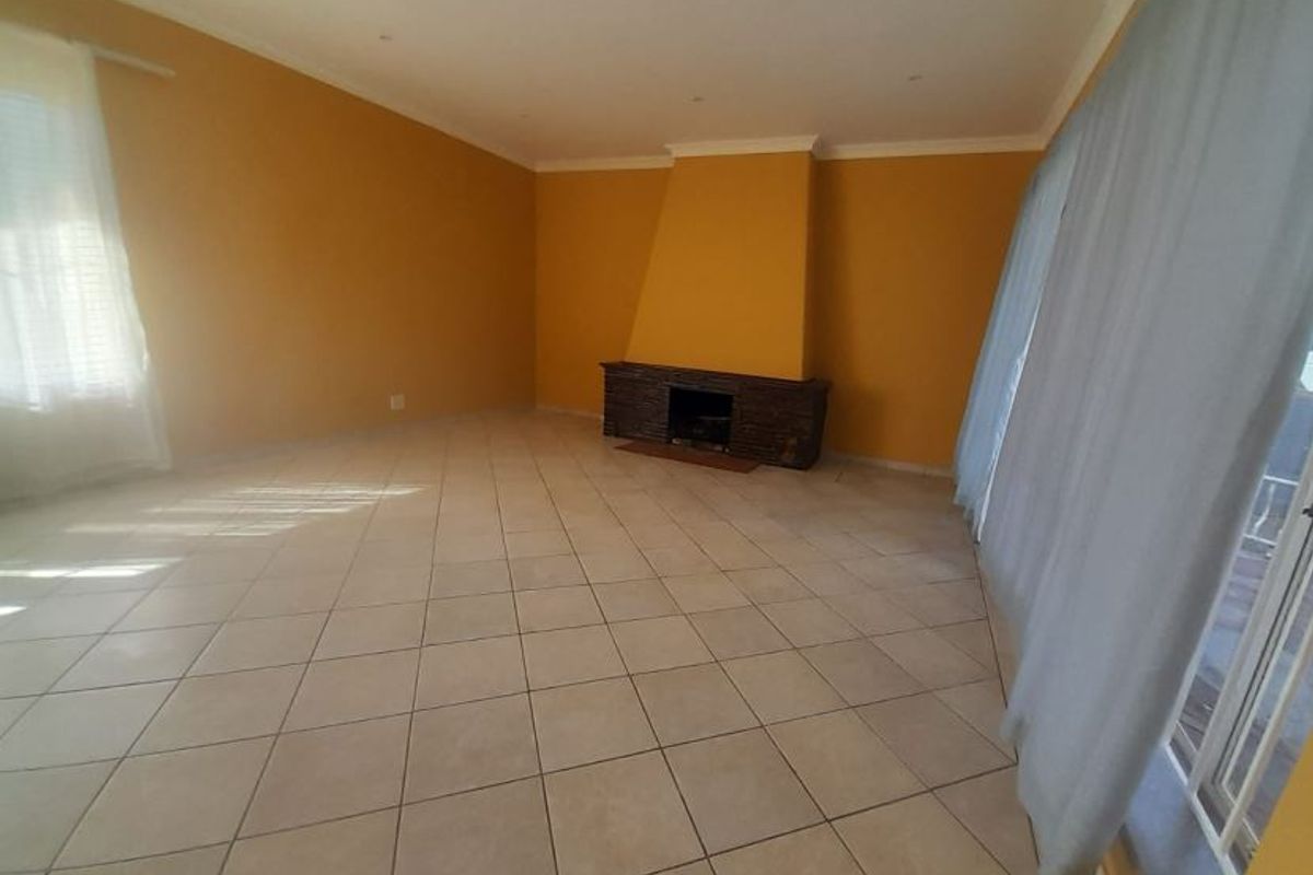 Spacious living room featuring tiled flooring, a central fireplace, and large sliding glass doors providing natural light and access to the exterior.