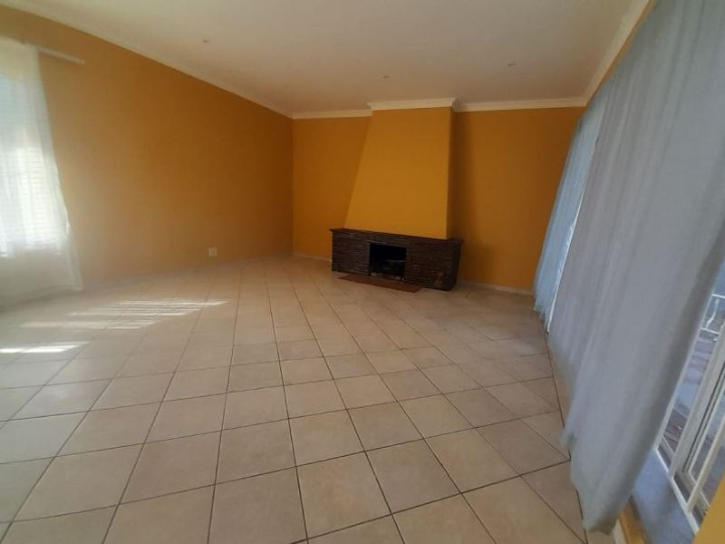 Spacious living room featuring tiled flooring, a central fireplace, and large sliding glass doors providing natural light and access to the exterior.