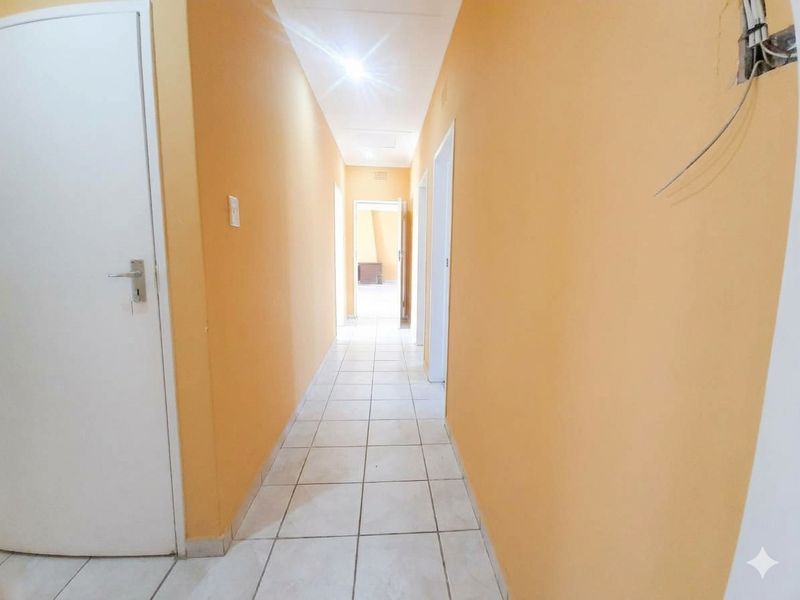 A vacant hallway featuring tiled flooring and multiple internal doors, currently requiring minor cosmetic repairs and finishing of electrical fixtures.