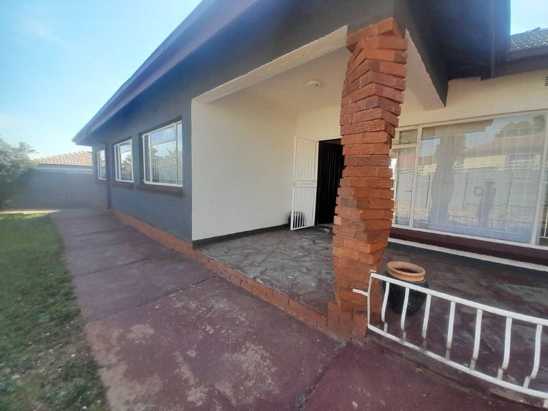 A covered patio area featuring a distinctive brick pillar, stone flooring, and metal security features, providing a functional outdoor space.