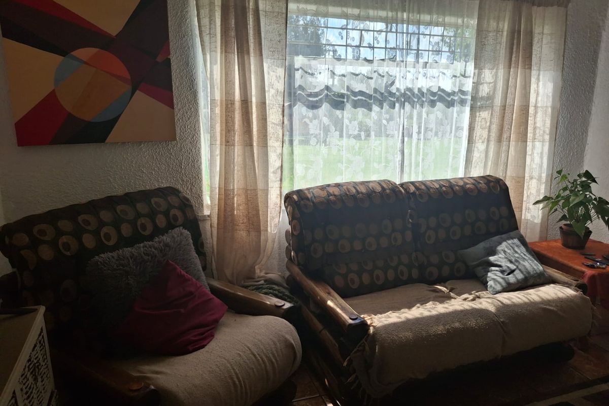 A cozy living room area featuring tiled flooring and a large window that allows for natural light.