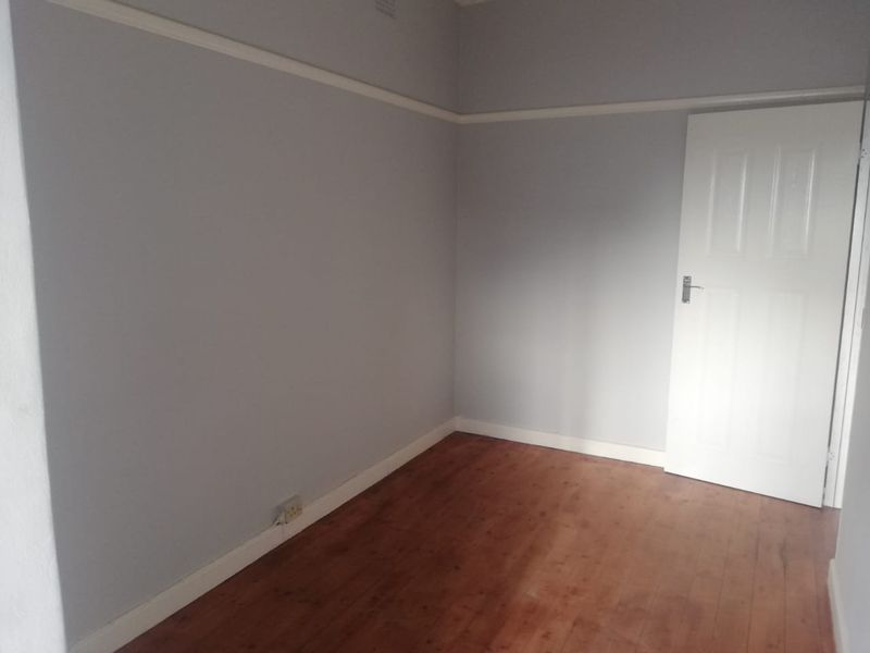 An empty bedroom featuring timber flooring, neutral wall paint, and classic picture rail detailing.