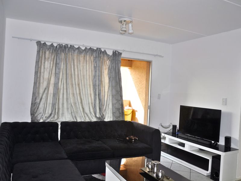 A living room featuring tiled flooring and a sliding door providing access to an outdoor area.