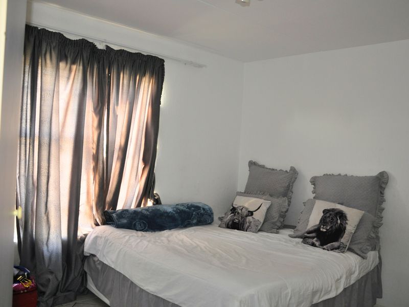 A simple bedroom featuring a window with installed curtain rails and neutral wall finishes.