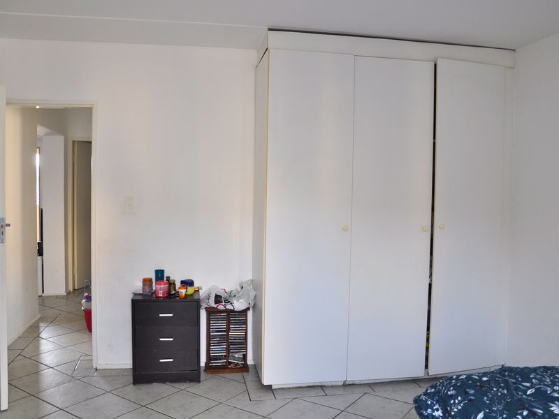 Bedroom featuring a large white built-in wardrobe and neutral tiled flooring, providing a functional storage solution within the space.