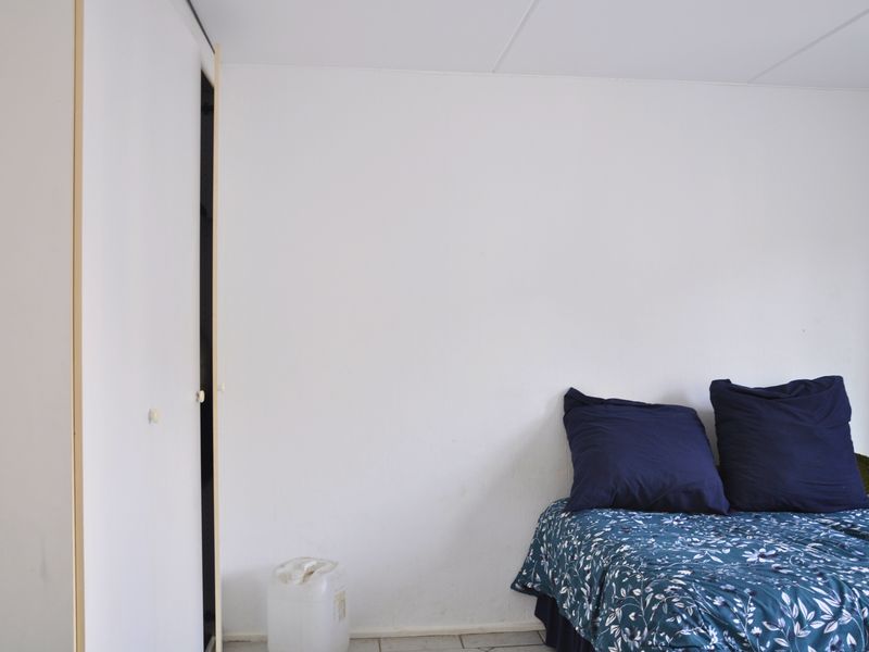 A simple bedroom featuring a built-in wardrobe with white doors and neutral wall finishes.
