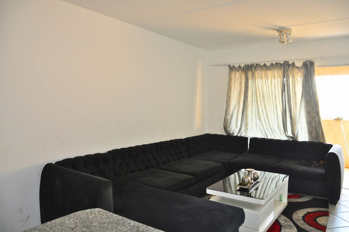 A living room area featuring a large window with curtain rod and ceiling lighting, providing a functional space for relaxation.